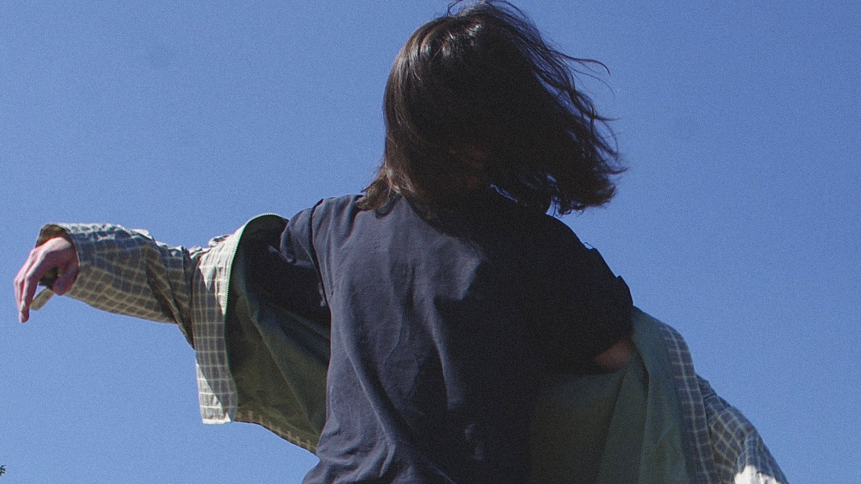 Model putting on a Ghostorchid checkered coat under open sky